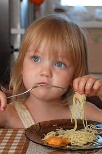 Маленькая девочка кушает макароны вилкой, скачать аватарку для контакта.